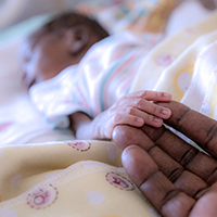 Fotografía de una madre sosteniendo la mano de su hija, que está enferma