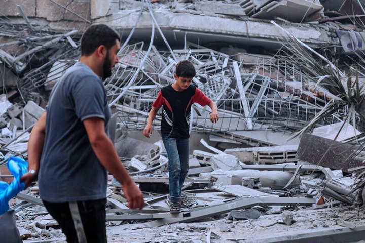 Fotografía de padre e hijo andando en Gaza, entre los derrumbes