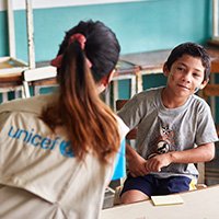 Fotografía de niño en sesión de atención psicosocial con una trabajadora de UNICEF