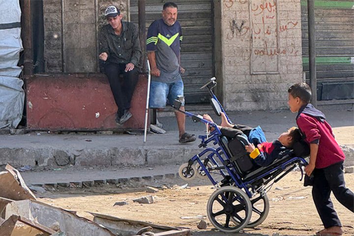 Niño llevando a otro en sillas de ruedas