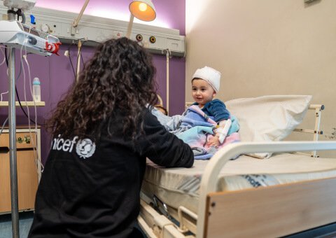 nina en hospital feliz con funcionaria de UNICEF