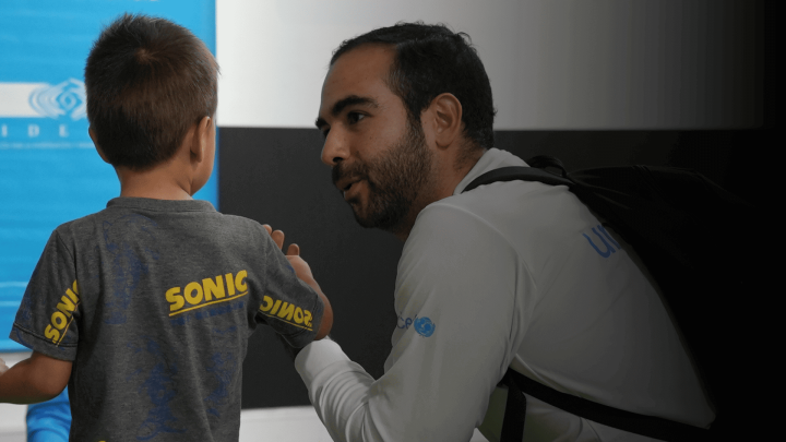 funcionario de UNICEf agachado hablando con niño para ayudarlo en la zon del catatumbo