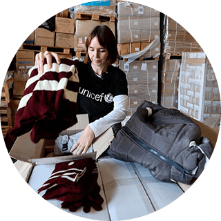 funcionaria de UNICEF ayudando a empacar kits de invierno