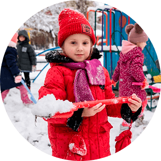 niña mirando a la camara mientras tiene una pala con nieve