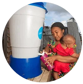 mujer con niño en brazos sacando agua de un filtro de UNICEF