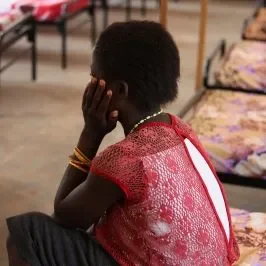 nina triste sentada en una cama dando la espalda a la camara